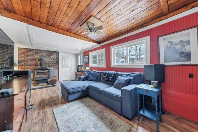 living room with a wood stove, wooden ceiling, ceiling fan, and wood-type flooring