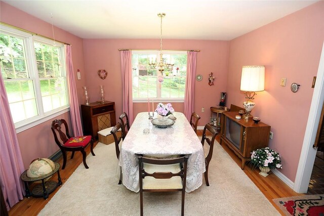 dining space with light hardwood / wood-style floors and an inviting chandelier