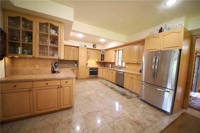 kitchen with decorative backsplash, light brown cabinetry, stainless steel appliances, and premium range hood