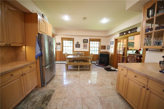 kitchen with a wood stove, french doors, a baseboard heating unit, stainless steel fridge, and light brown cabinetry