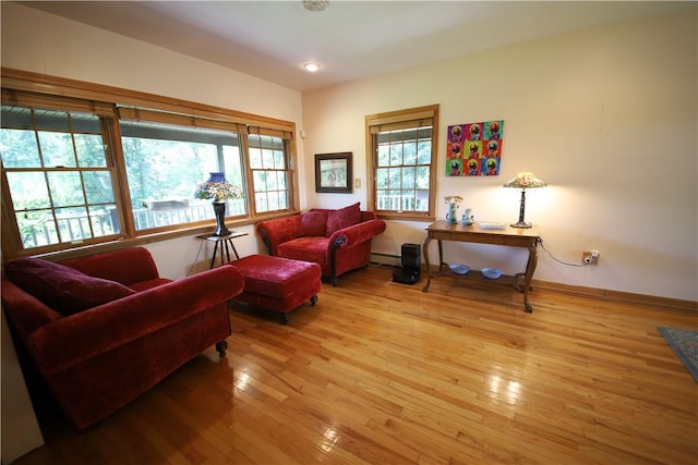 living room featuring light wood-type flooring, a wealth of natural light, and a baseboard heating unit