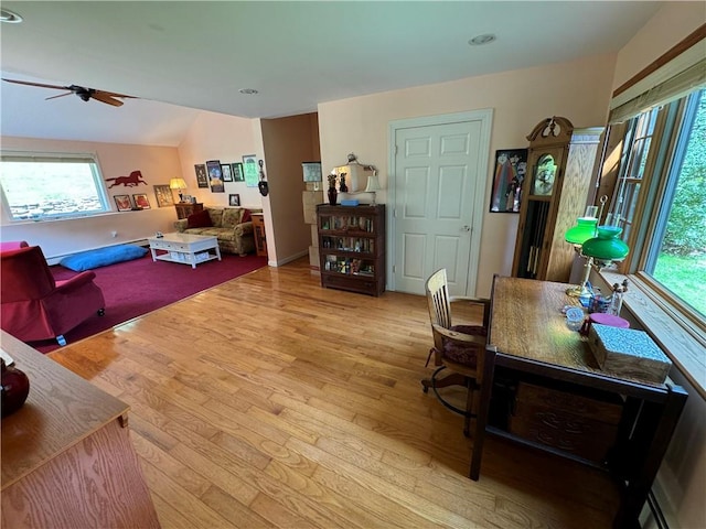 living room featuring ceiling fan, light hardwood / wood-style floors, and vaulted ceiling