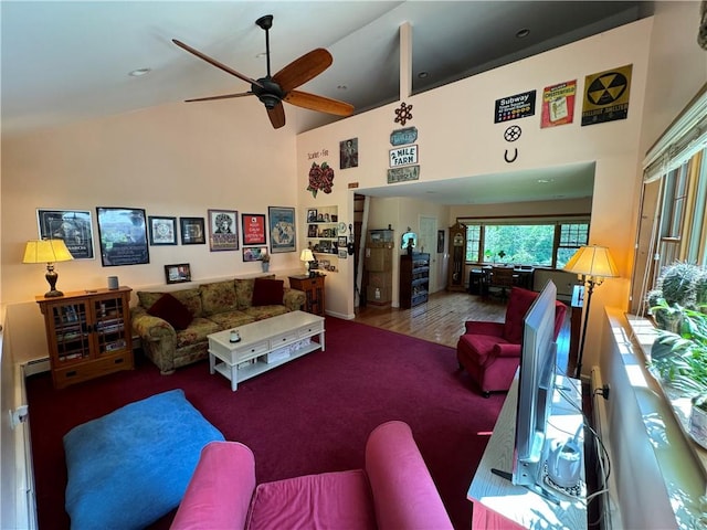 living room with ceiling fan, wood-type flooring, and a high ceiling