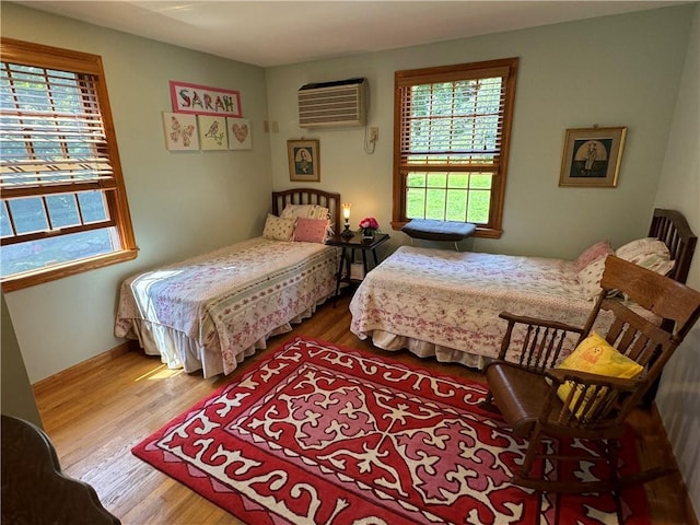 bedroom with an AC wall unit and hardwood / wood-style floors