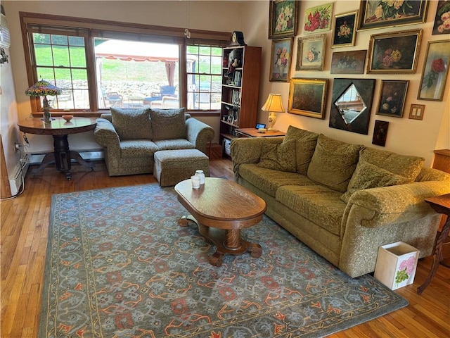 living room with wood-type flooring, a baseboard radiator, and a wealth of natural light