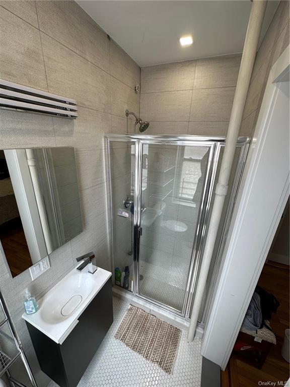 bathroom featuring tile walls, vanity, and an enclosed shower