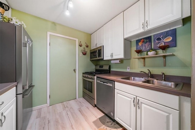 kitchen with sink, white cabinetry, stainless steel appliances, and light hardwood / wood-style flooring