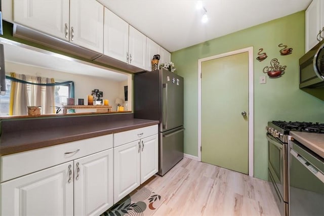 kitchen featuring white cabinets, stainless steel appliances, and light wood-type flooring