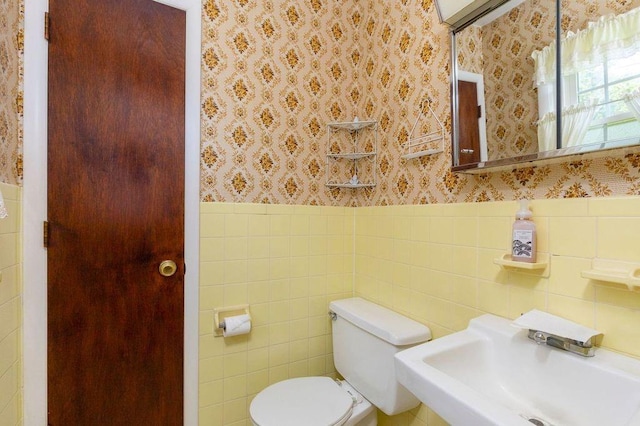 bathroom featuring sink, tile walls, and toilet