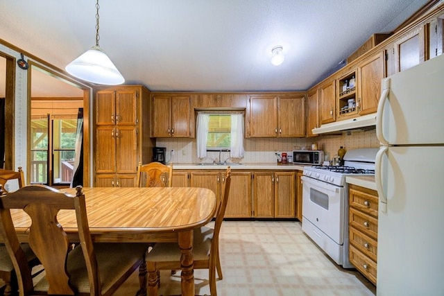 kitchen with white appliances, tasteful backsplash, hanging light fixtures, and sink