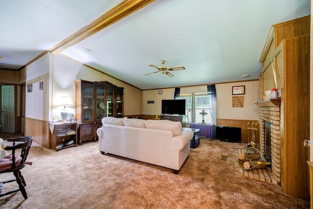 living room with ornamental molding, light colored carpet, ceiling fan, a fireplace, and wood walls