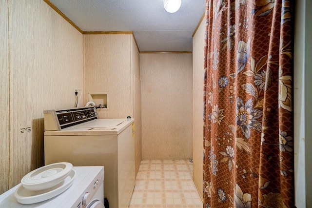 washroom featuring a textured ceiling, washer and clothes dryer, and crown molding