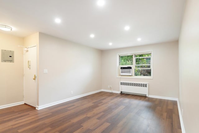 unfurnished living room with radiator heating unit, dark wood-type flooring, and electric panel