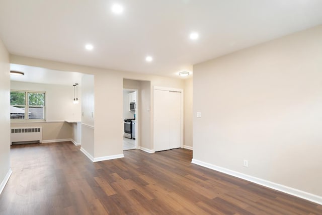 unfurnished room with radiator heating unit and dark wood-type flooring