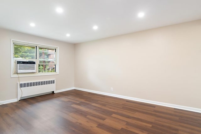 spare room with radiator heating unit, cooling unit, and dark wood-type flooring