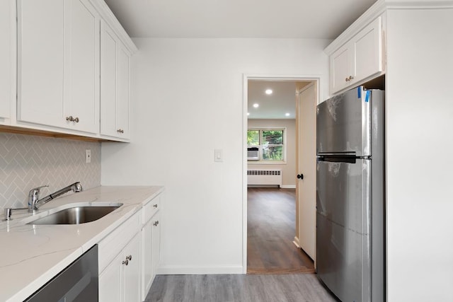 kitchen featuring white cabinets, radiator, sink, and appliances with stainless steel finishes