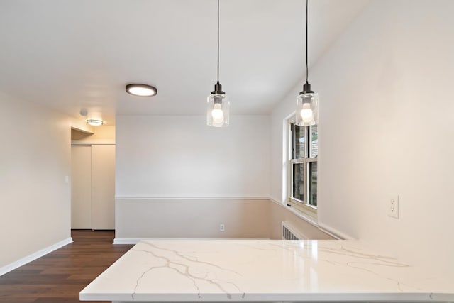 kitchen featuring light stone countertops, pendant lighting, and dark wood-type flooring