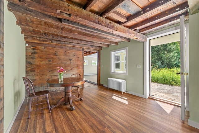 unfurnished dining area featuring beamed ceiling, wood-type flooring, radiator heating unit, and wood ceiling