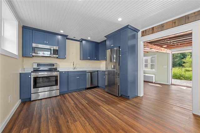 kitchen featuring blue cabinetry, radiator, dark hardwood / wood-style flooring, and appliances with stainless steel finishes