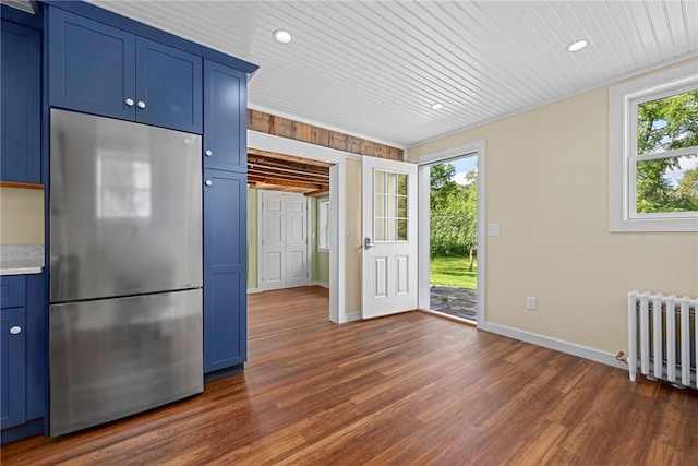 kitchen featuring blue cabinetry, stainless steel refrigerator, plenty of natural light, and radiator