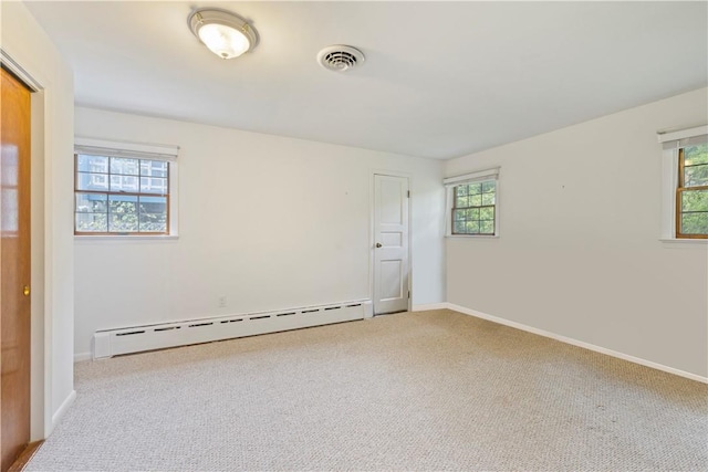 carpeted empty room featuring a baseboard heating unit