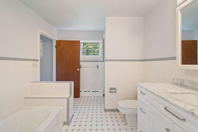 bathroom featuring a washtub, a baseboard heating unit, toilet, vanity, and tile walls