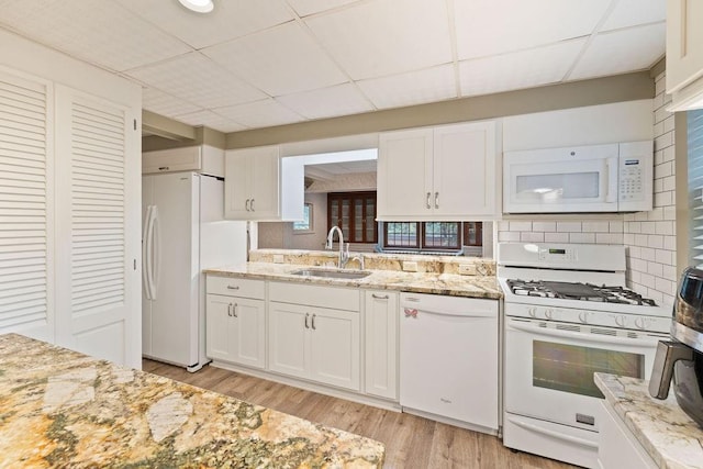 kitchen with a paneled ceiling, white appliances, sink, light hardwood / wood-style floors, and white cabinetry