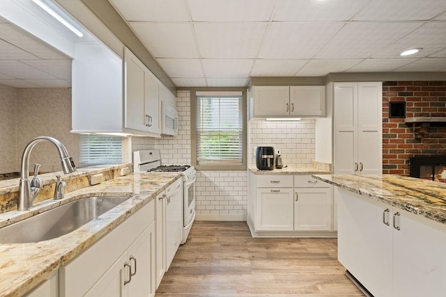 kitchen with white cabinetry, sink, light hardwood / wood-style floors, and white appliances