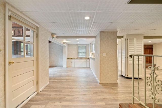 corridor featuring light hardwood / wood-style flooring, a healthy amount of sunlight, and a baseboard radiator