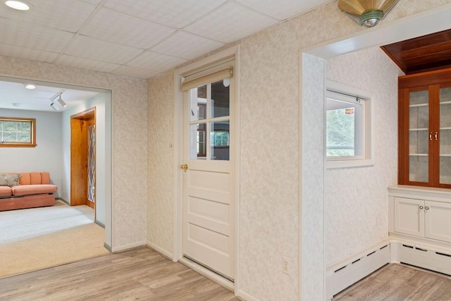 hallway featuring plenty of natural light, baseboard heating, and light hardwood / wood-style flooring