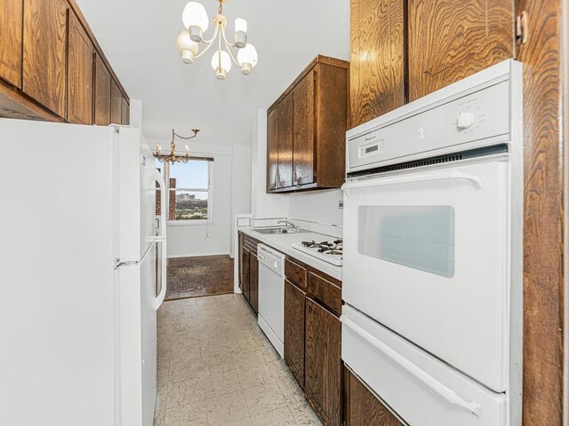 kitchen with white appliances, sink, and a chandelier