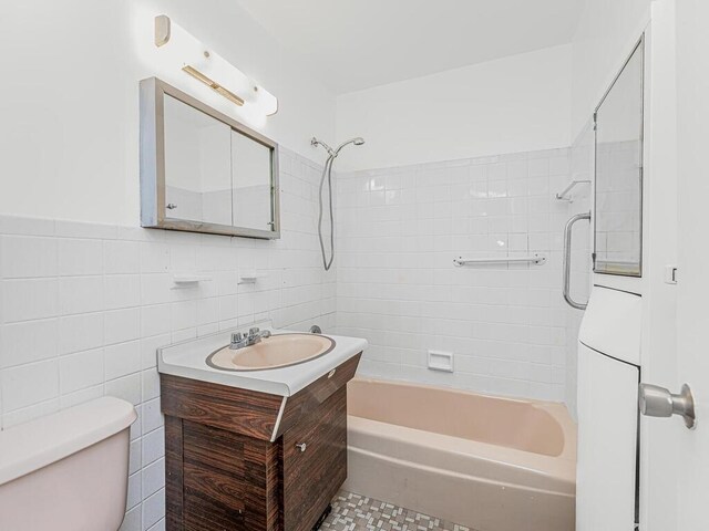 full bathroom with vanity, toilet, tile walls, and tiled shower / bath