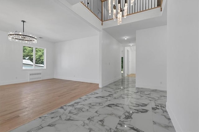 unfurnished living room featuring light wood-type flooring and an inviting chandelier