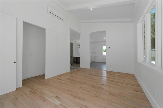 unfurnished room featuring light hardwood / wood-style flooring, lofted ceiling with beams, and a wall mounted air conditioner