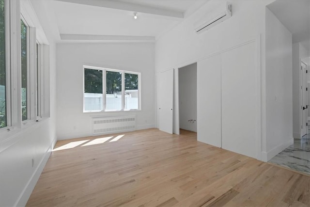 3 Forshee St, Monroe, NY 10950 - empty room featuring radiator heating unit, a wall mounted air conditioner, light wood-style floors, and beam ceiling