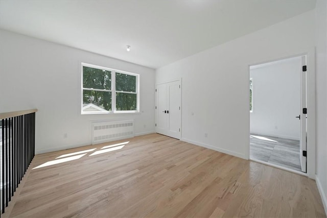 empty room with radiator heating unit and light hardwood / wood-style floors