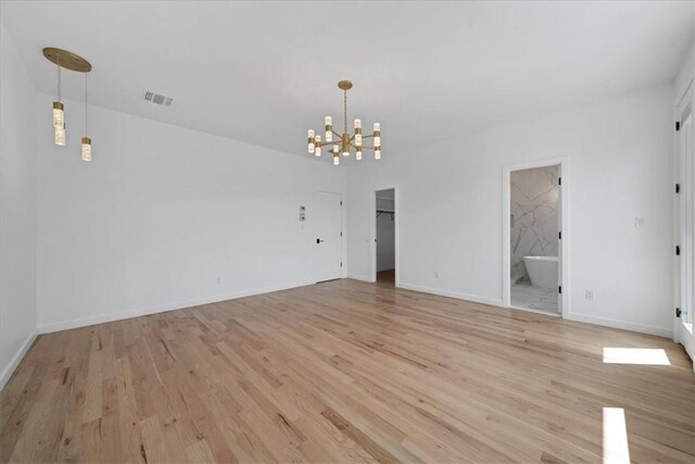 empty room with light hardwood / wood-style floors and an inviting chandelier