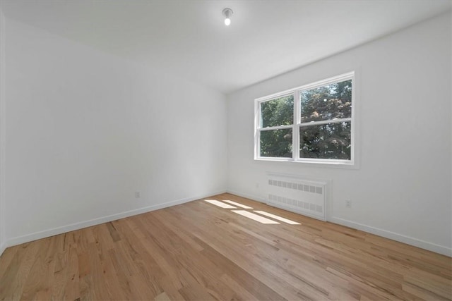 unfurnished room featuring radiator heating unit and light hardwood / wood-style flooring