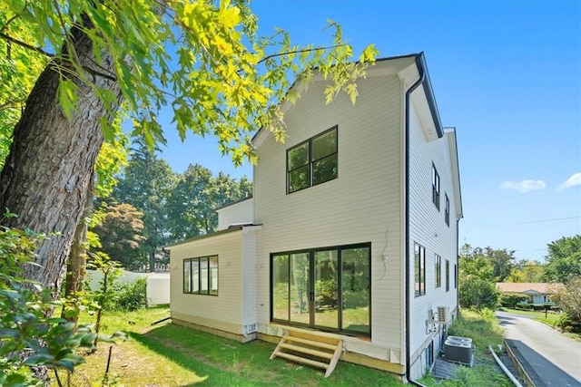 rear view of property featuring a yard and central air condition unit