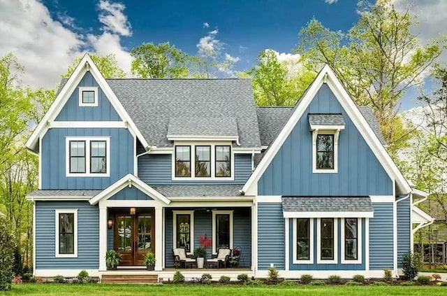 rear view of property featuring a lawn, a porch, and french doors