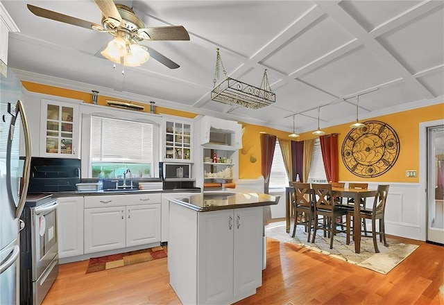 kitchen with a healthy amount of sunlight, white cabinetry, a kitchen island, and stainless steel stove