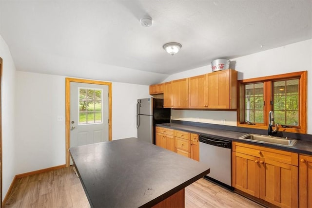 kitchen featuring appliances with stainless steel finishes, light wood-type flooring, sink, a kitchen island, and lofted ceiling