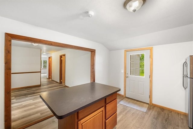 kitchen featuring stainless steel refrigerator, lofted ceiling, and light wood-type flooring