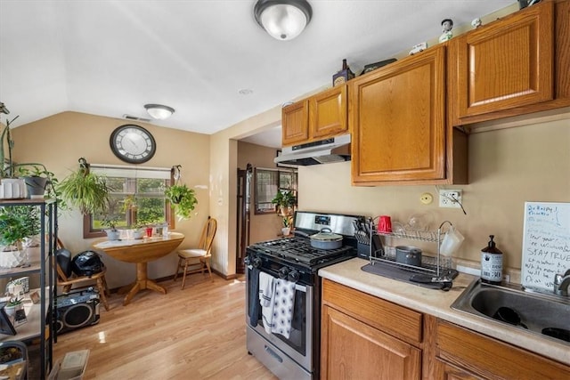 kitchen featuring gas stove, light hardwood / wood-style floors, sink, and vaulted ceiling