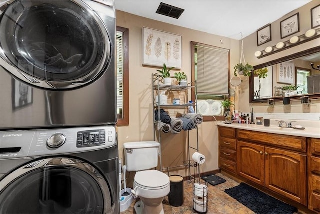 laundry area with stacked washer and dryer and sink