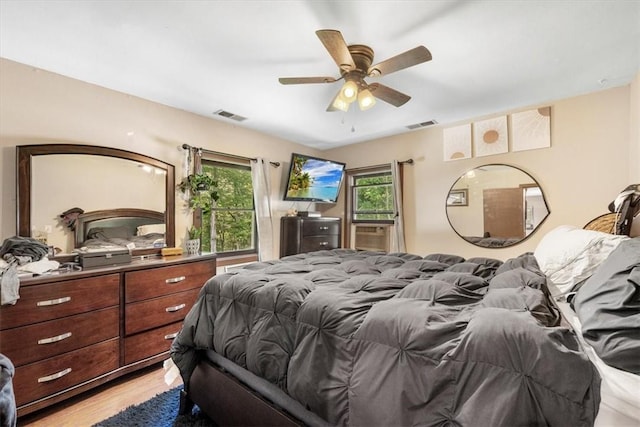 bedroom featuring ceiling fan, light hardwood / wood-style floors, and multiple windows