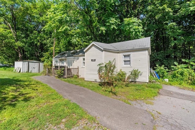 view of side of property with a deck, a storage shed, and a lawn