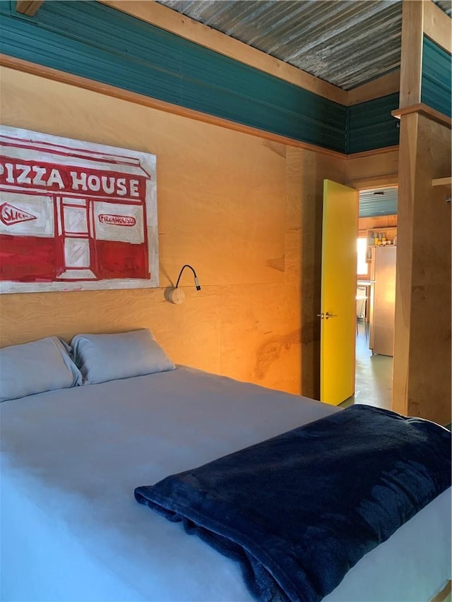 bedroom with concrete flooring and fridge