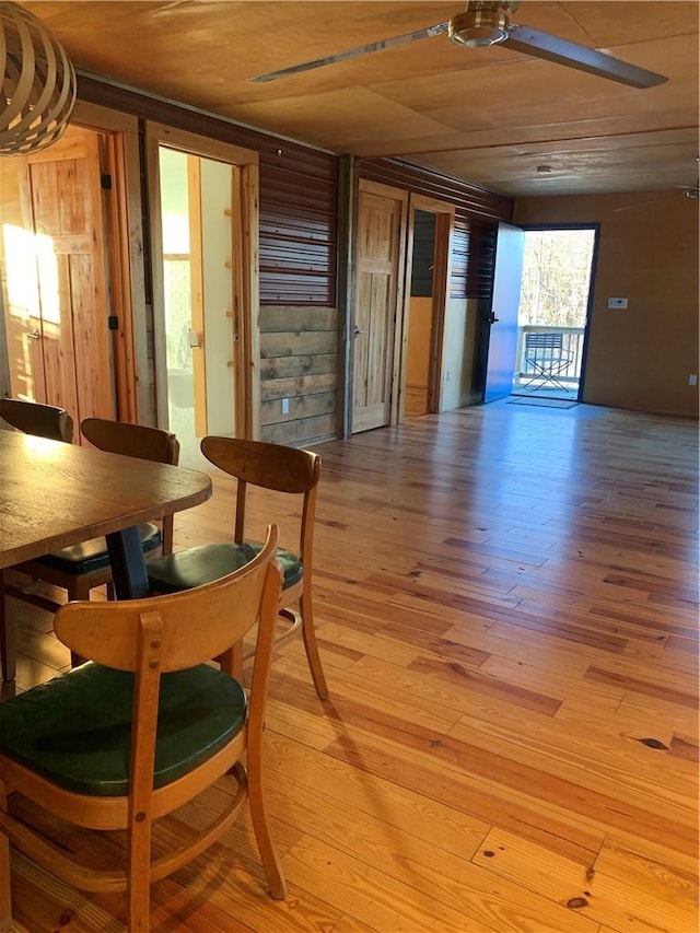 dining area featuring ceiling fan, wood ceiling, wood walls, and light wood-type flooring