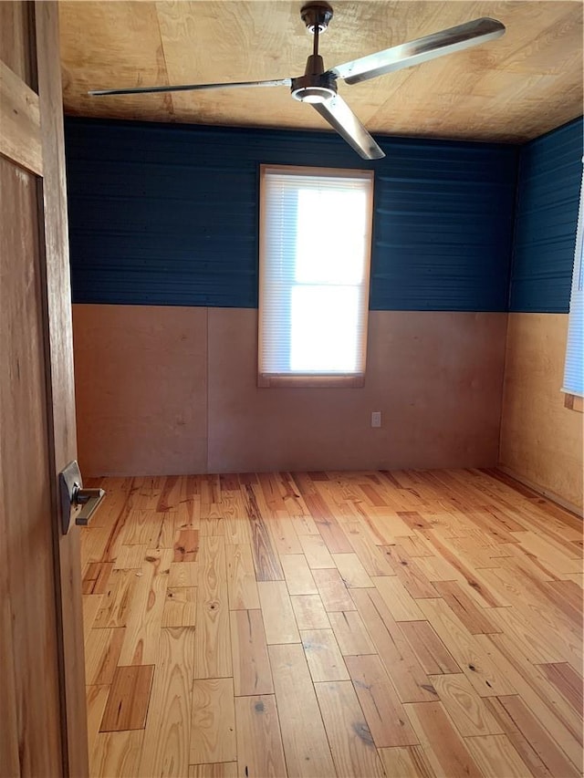 spare room featuring wood walls and light hardwood / wood-style floors